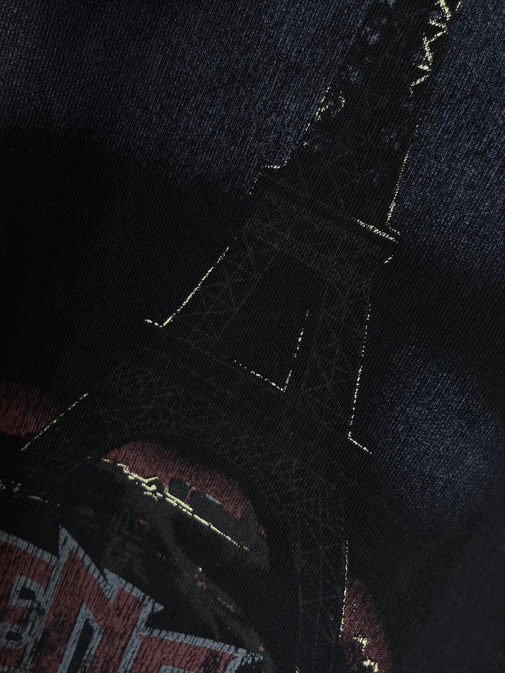 Graphic T-shirt close-up, band-style letters in red and blue with yellow accents
