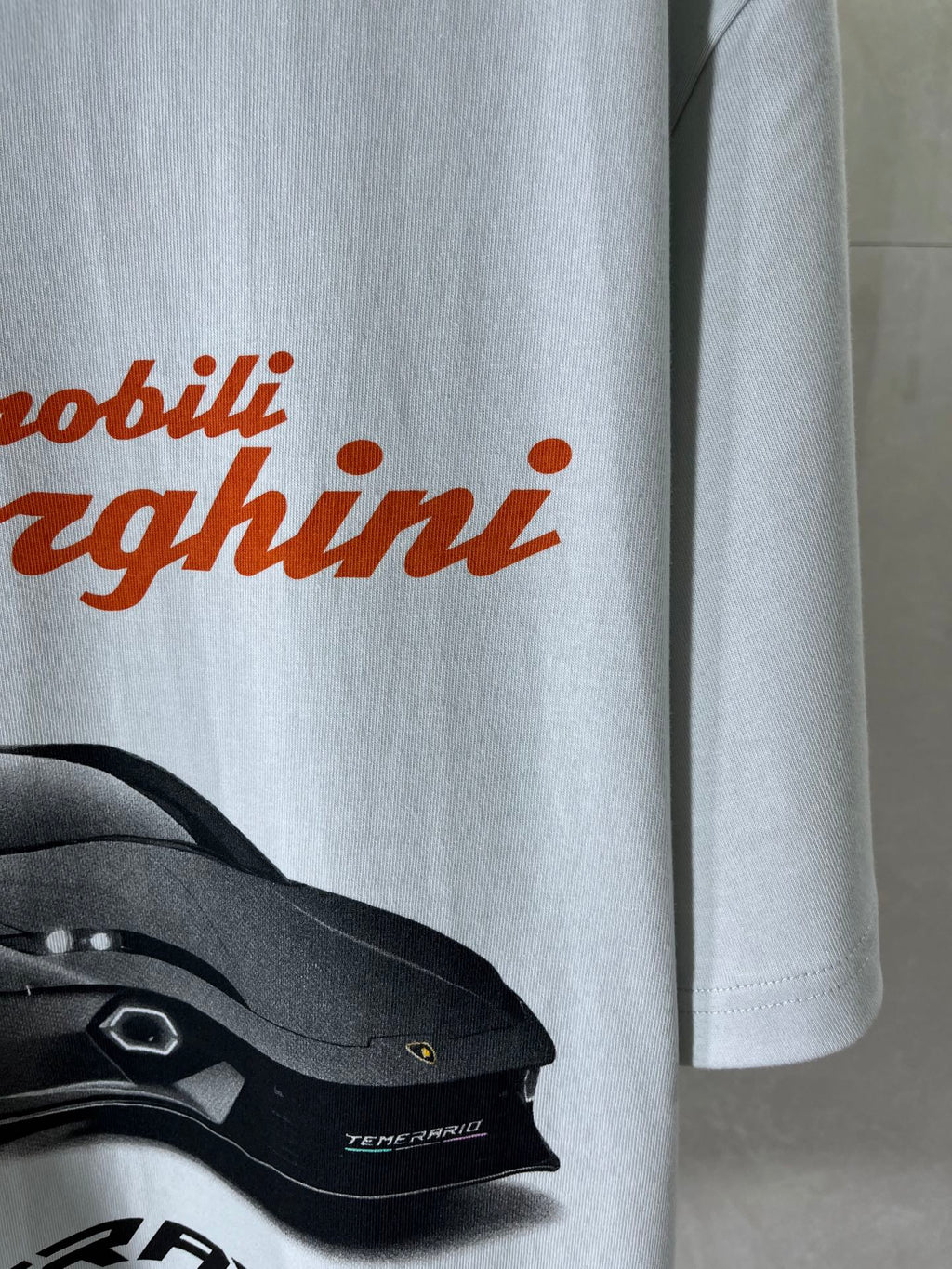 Light blue T-shirt front with orange Lamborghini text and car graphic