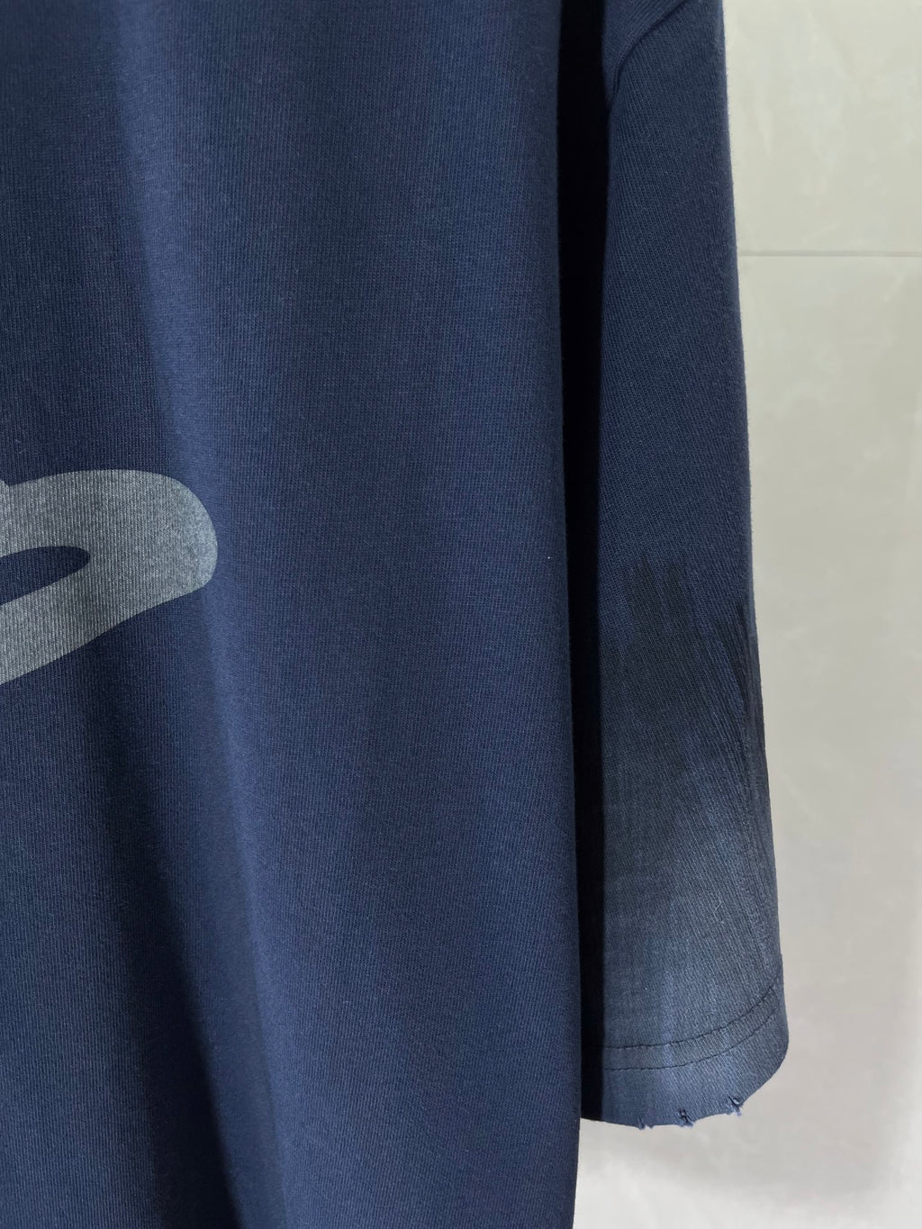 Navy crew-neck T-shirt sleeve and side seam with partial grey logo graphic