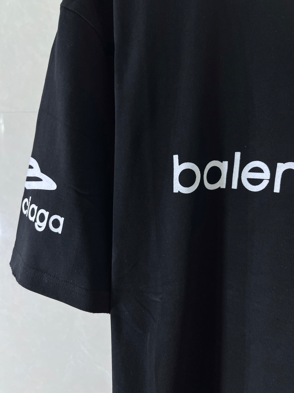 Dark navy T-shirt side view with 'balenciaga' logo sleeve print