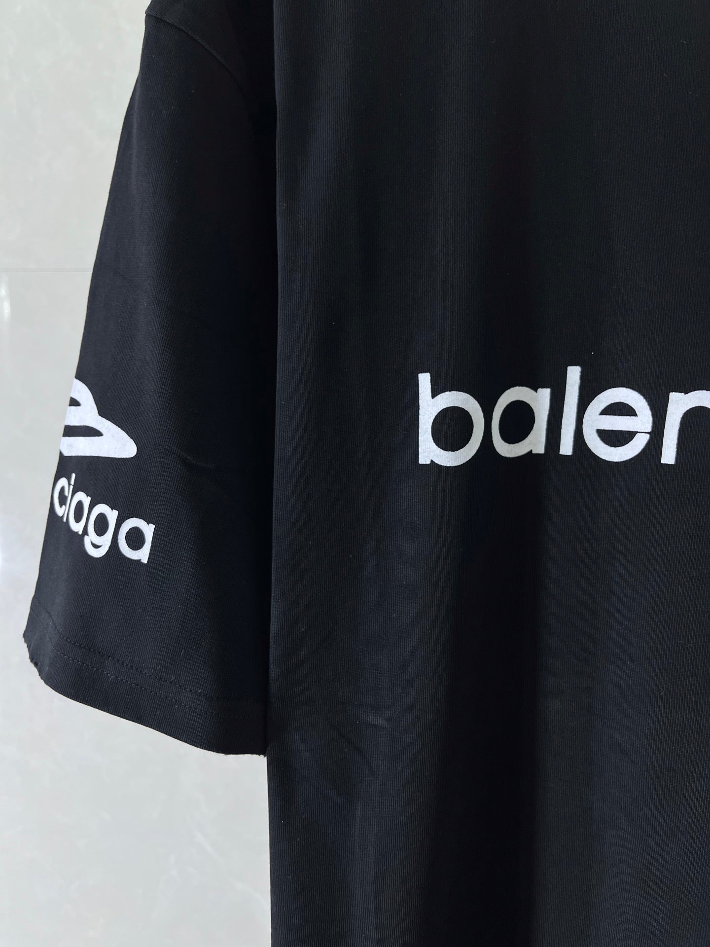 Dark navy T-shirt side view with 'balenciaga' logo sleeve print