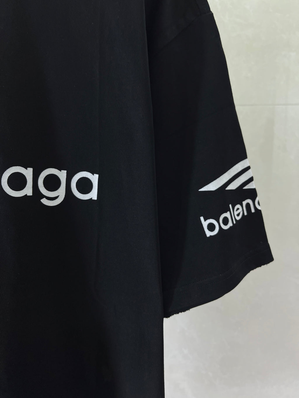 Dark navy T-shirt sleeve detail with 'balenciaga' and geometric mark