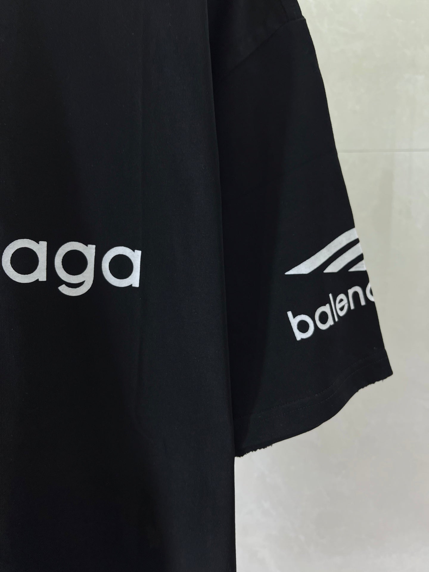 Dark navy T-shirt sleeve detail with 'balenciaga' and geometric mark