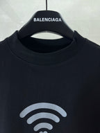 Black T-shirt neckline with small white Wi‑Fi icon and BALENCIAGA chest print