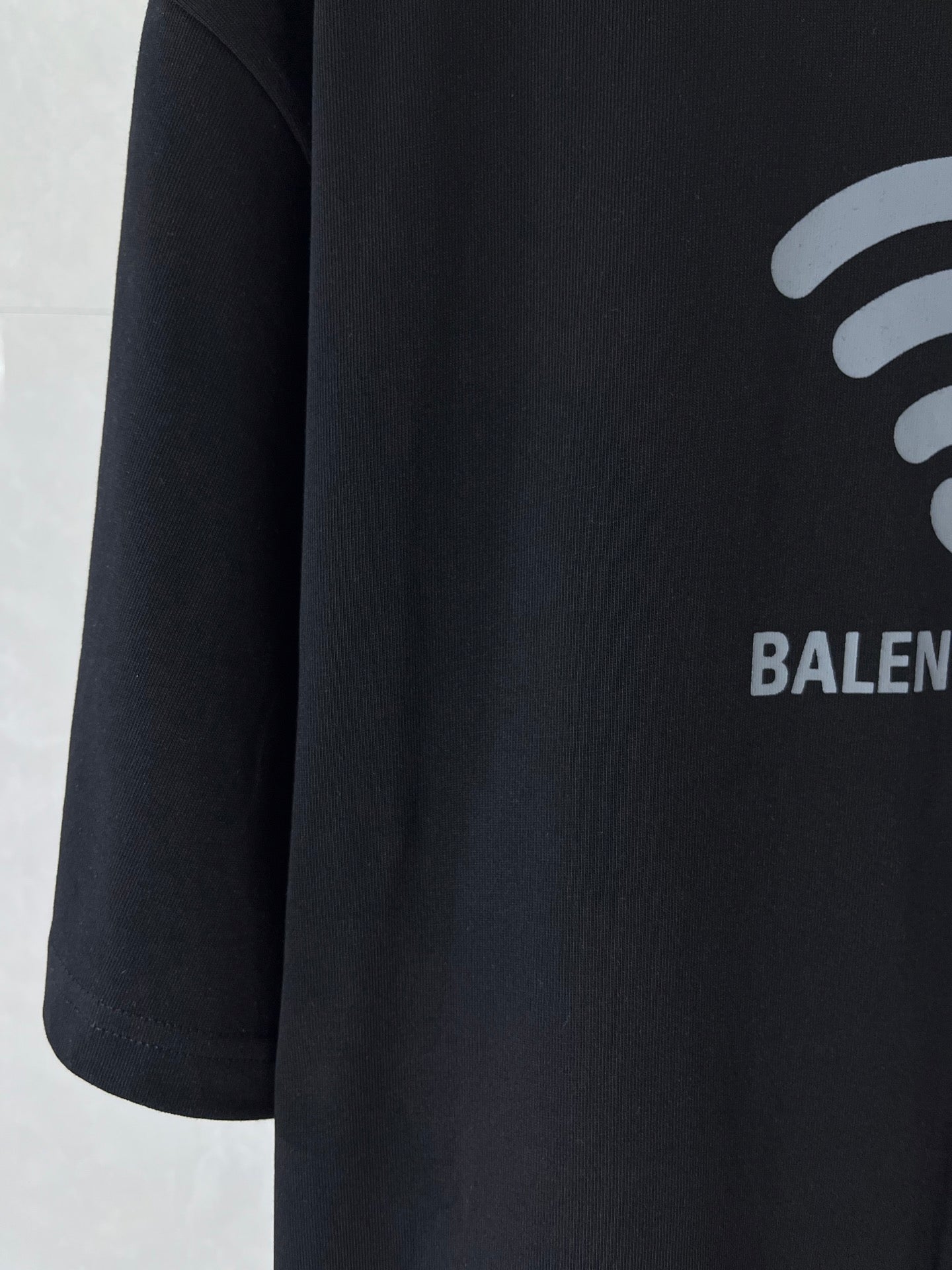 Black T-shirt with partial white Wi‑Fi icon and BALENCIAGA print on right