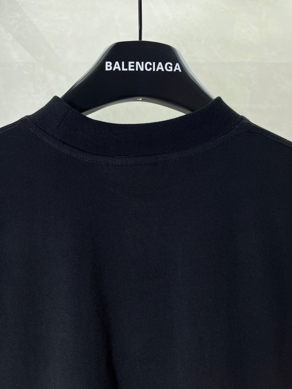 Black T-shirt collar and upper front panel on hanger with BALENCIAGA label