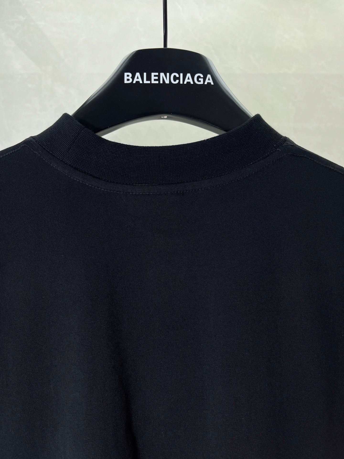 Black T-shirt collar and upper front panel on hanger with BALENCIAGA label
