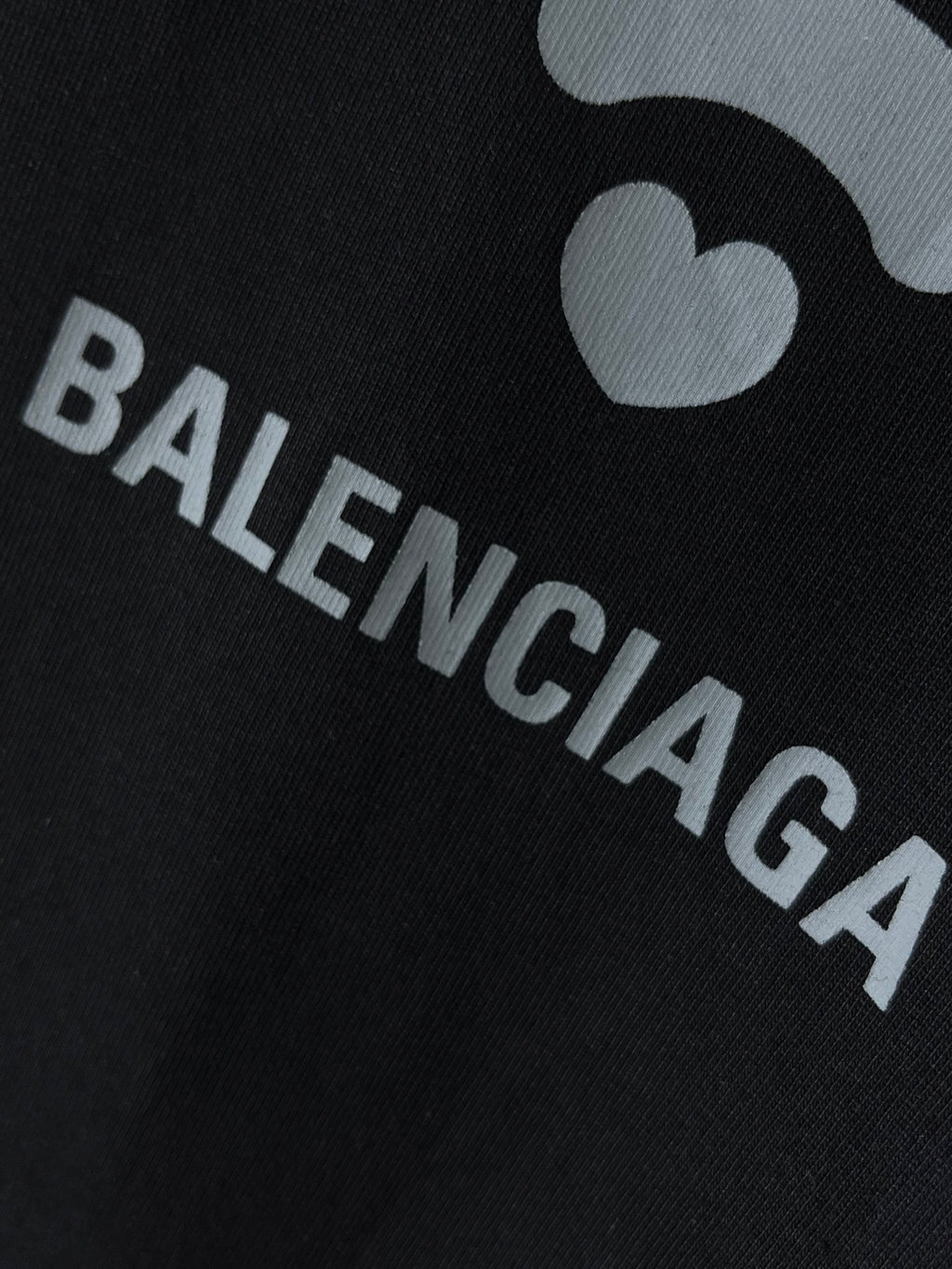 Black T-shirt fabric close-up with BALENCIAGA letters and Wi‑Fi icon