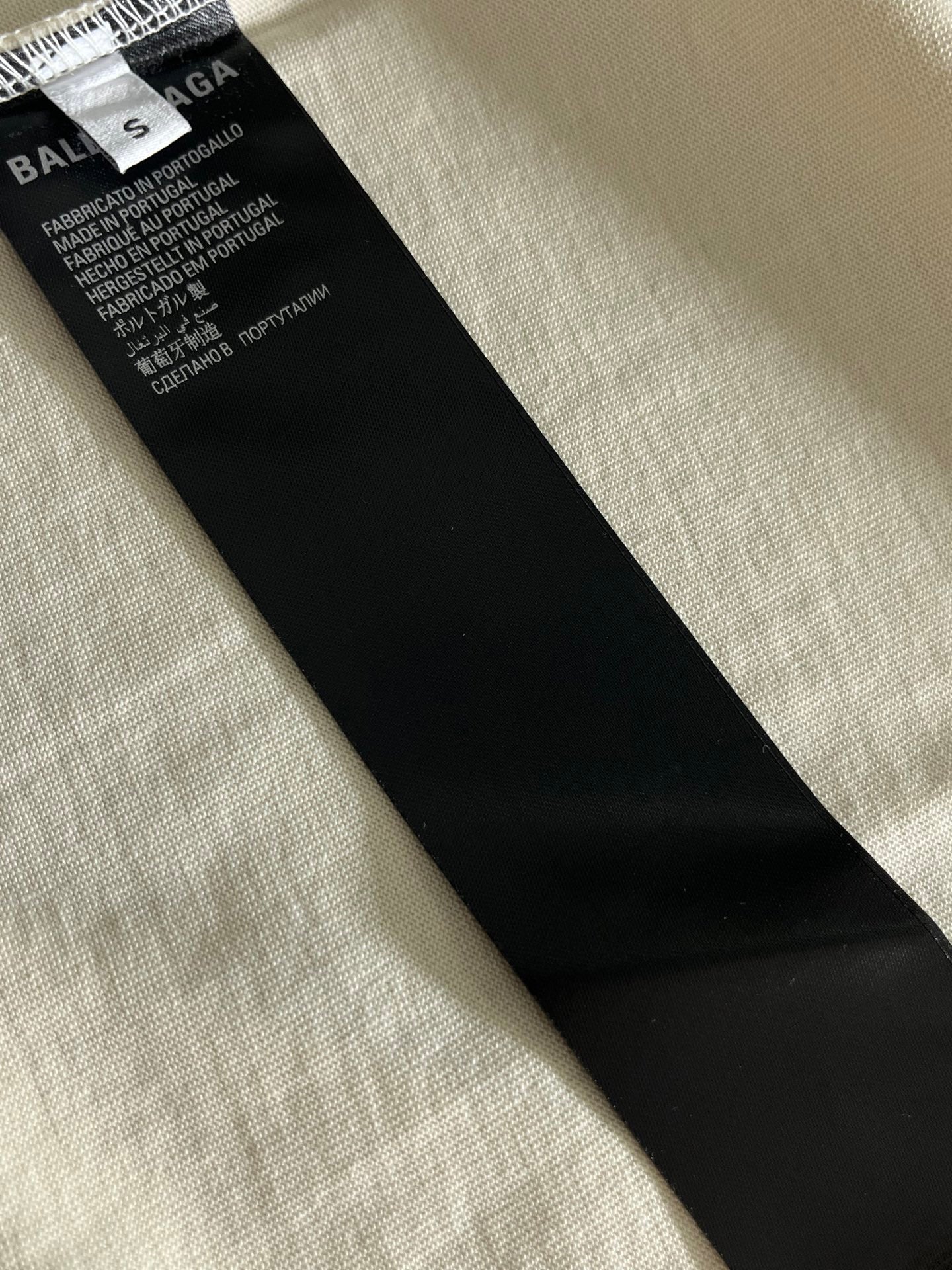 Inside care label on white short-sleeve T-shirt, black fabric tag with text