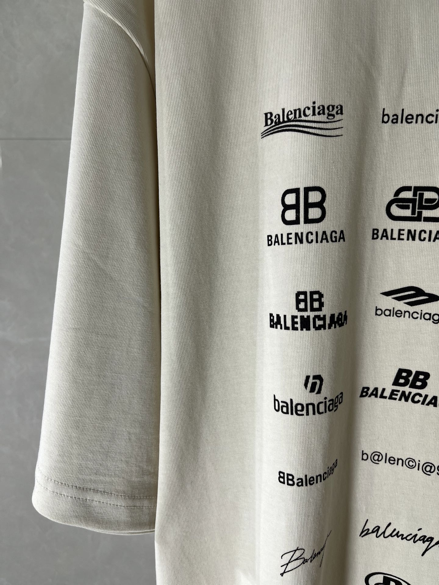 White T-shirt sleeve and front logos, including Balenciaga and signature-style marks