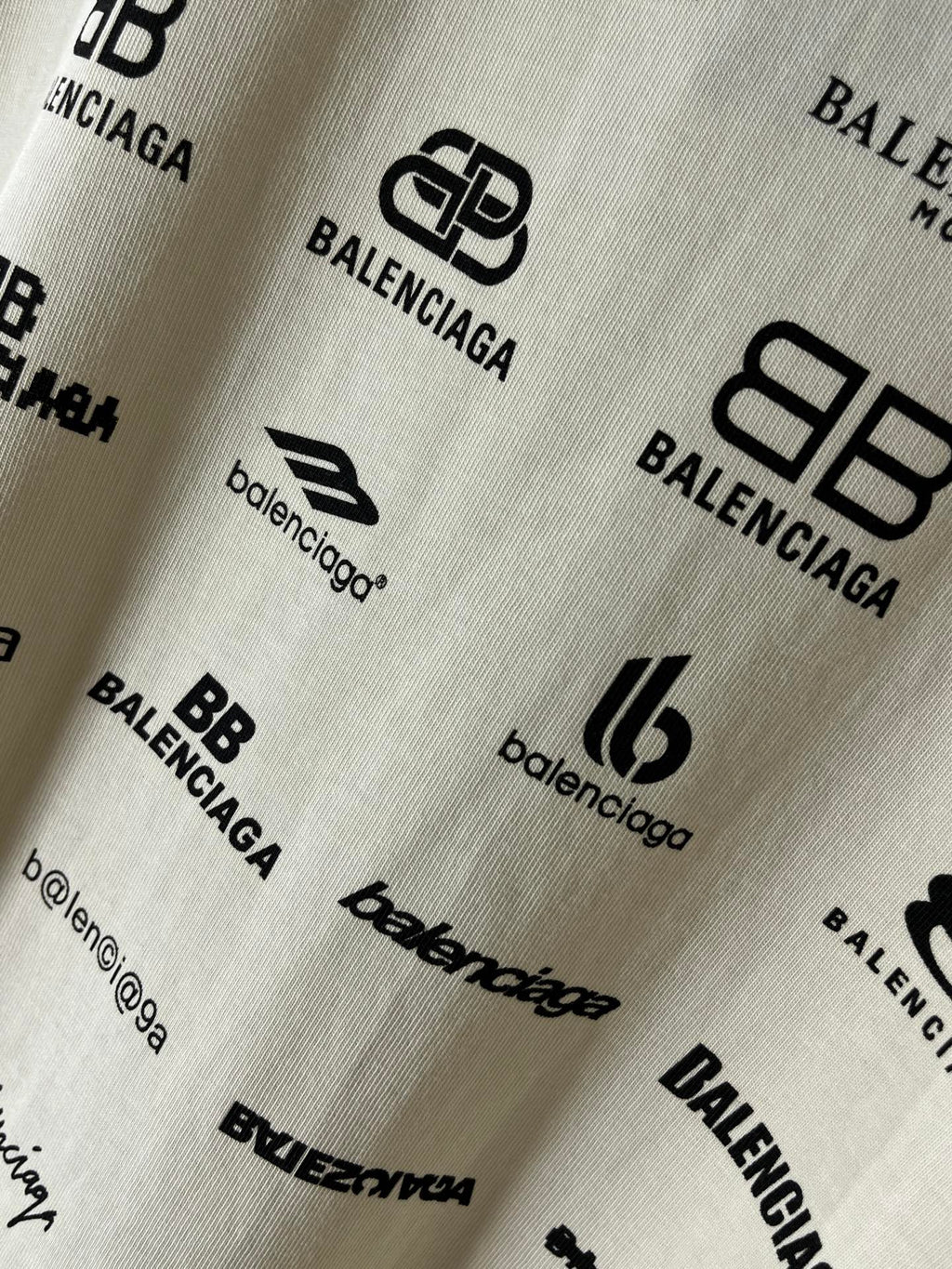 Close-up of white fabric with Balenciaga logo and emblem prints