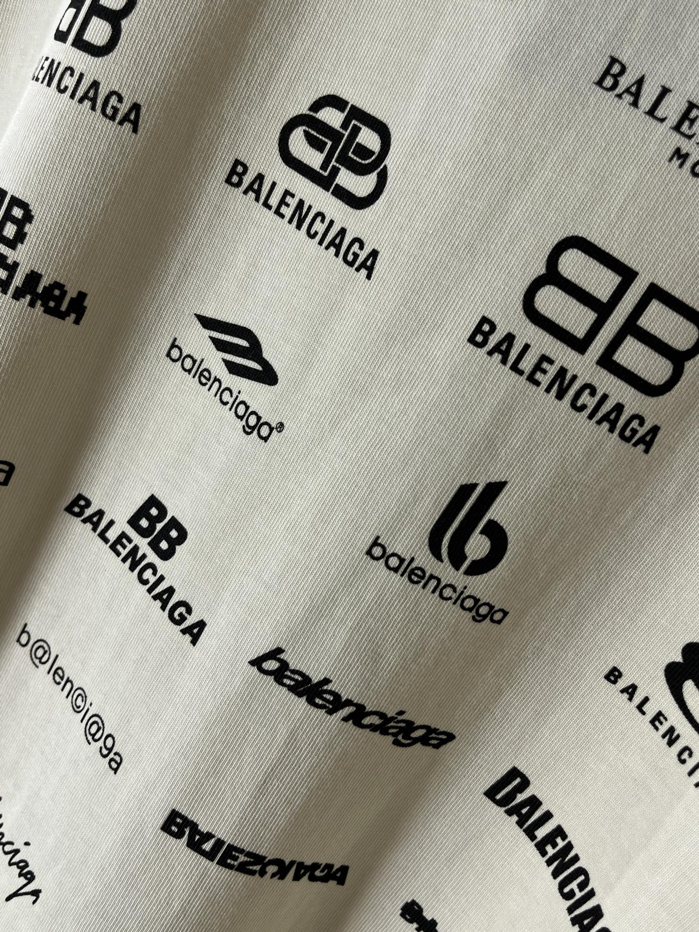 Close-up of white fabric with Balenciaga logo and emblem prints