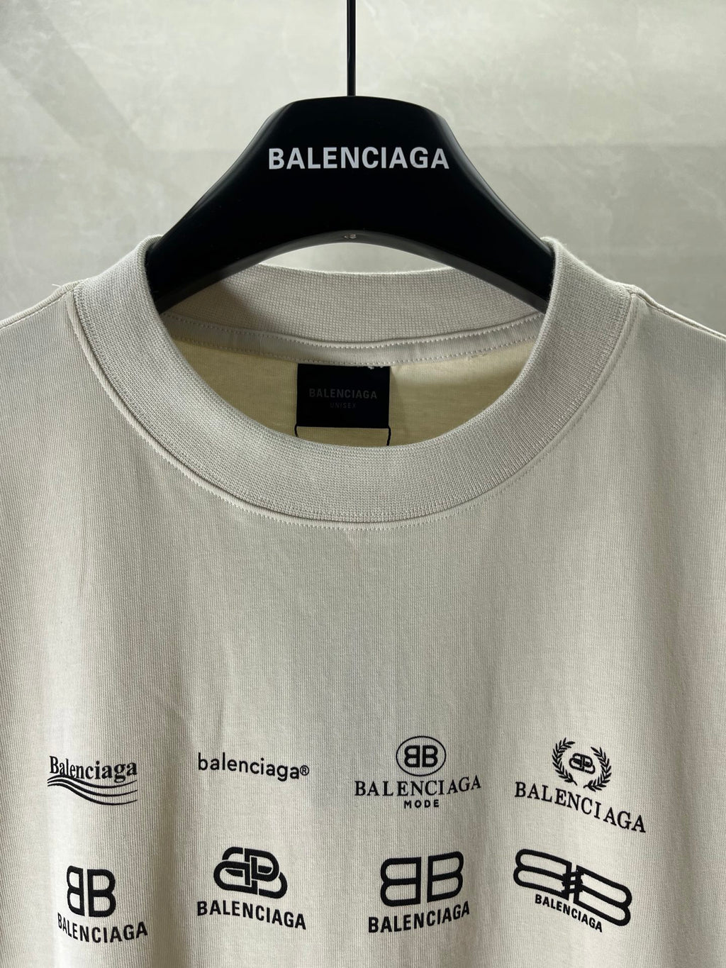 White short-sleeve T-shirt neckline and front graphic logos, on a hanger