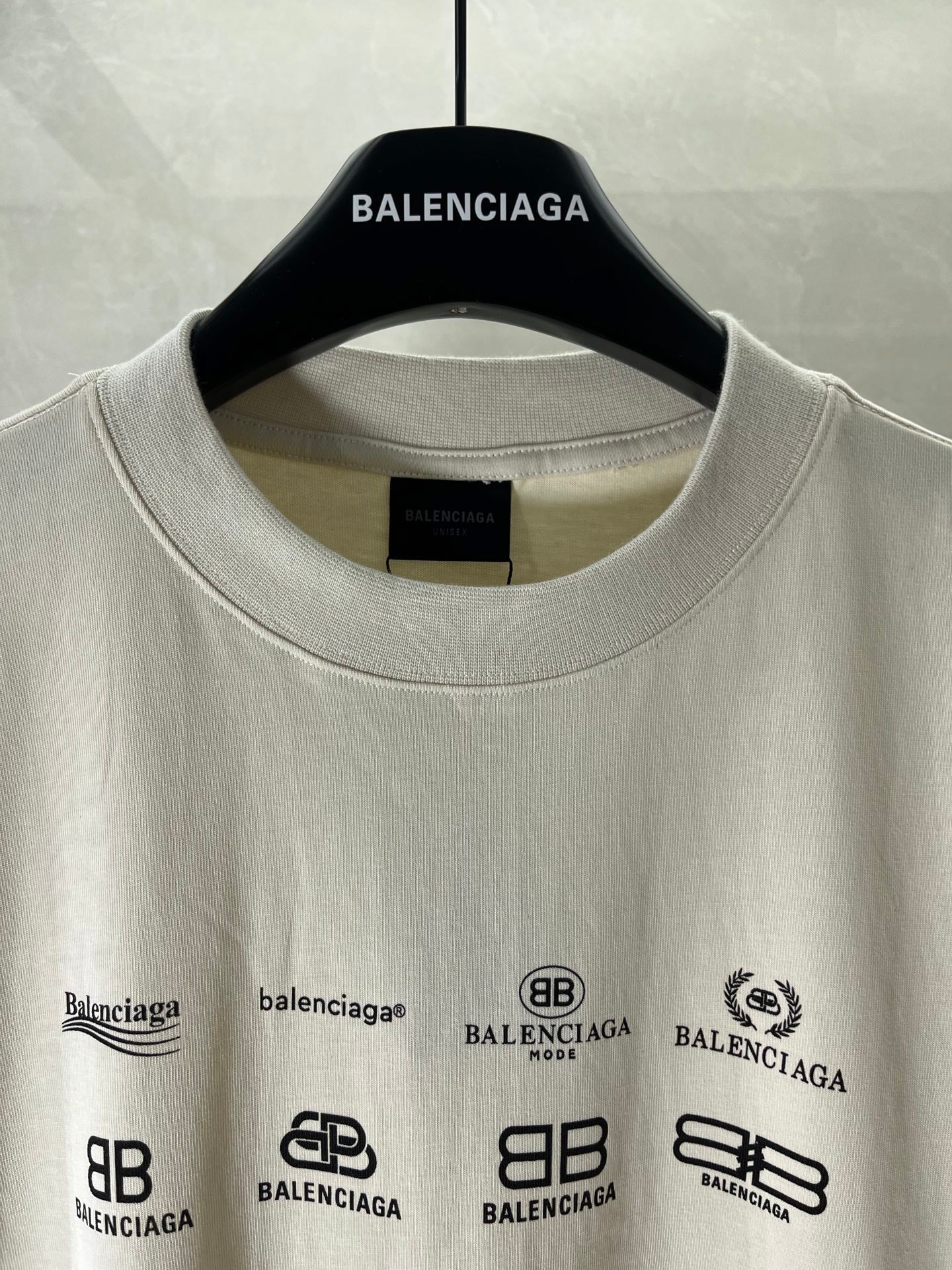 White short-sleeve T-shirt neckline and front graphic logos, on a hanger