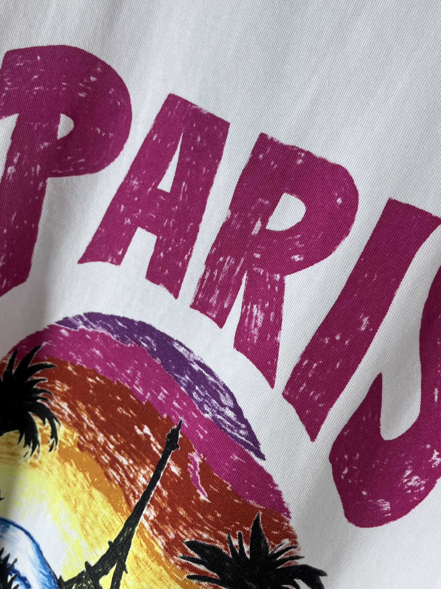 Balenciaga T-shirt close-up: magenta “PARIS” text above palm tree graphic