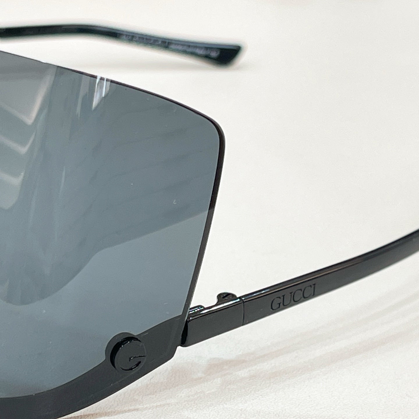 Gucci glasses close-up: black frame with blue tinted lens, gold-tone arm