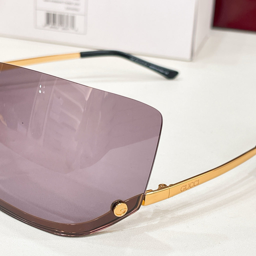 Gucci square sunglasses close-up with gold temple detail and mauve tinted lenses