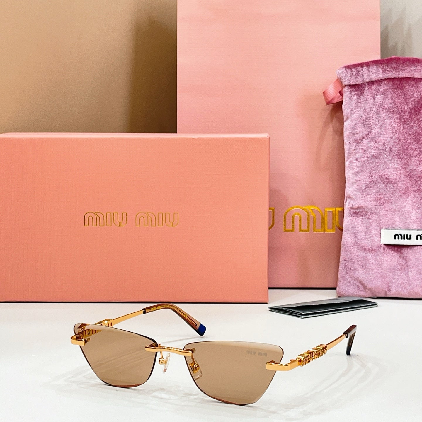 MiuMiu cat-eye sunglasses, gold frame with blue accents, warm brown tinted lenses