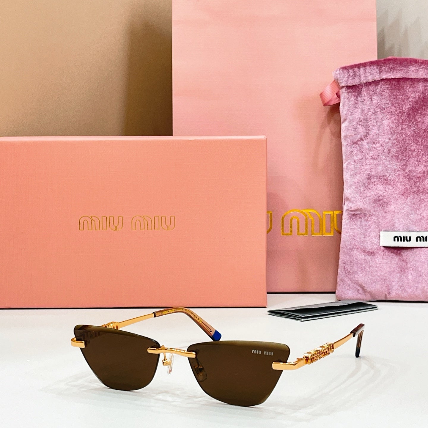 MiuMiu cat-eye sunglasses, gold frames and blue-tipped temples, dark-brown lenses