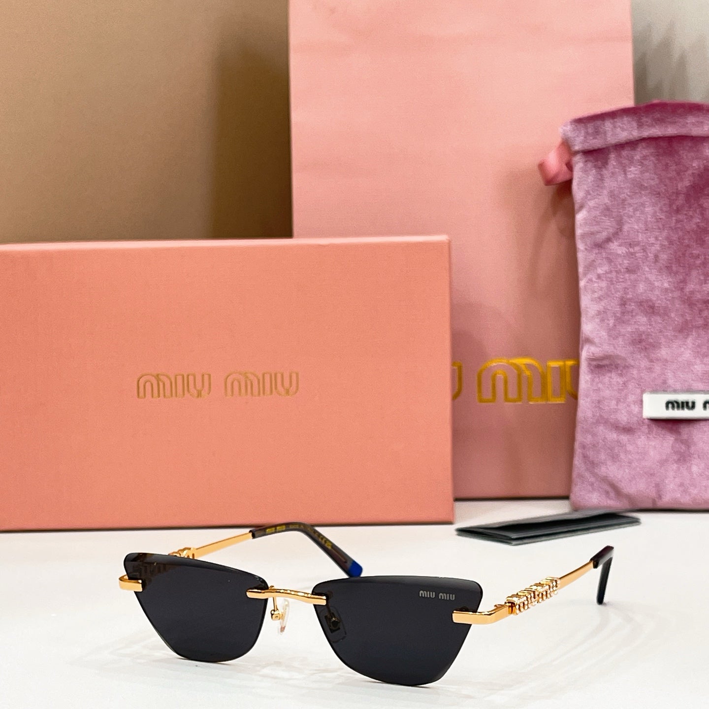 MiuMiu cat-eye sunglasses, black-tinted lenses with gold frames and blue-tipped temples