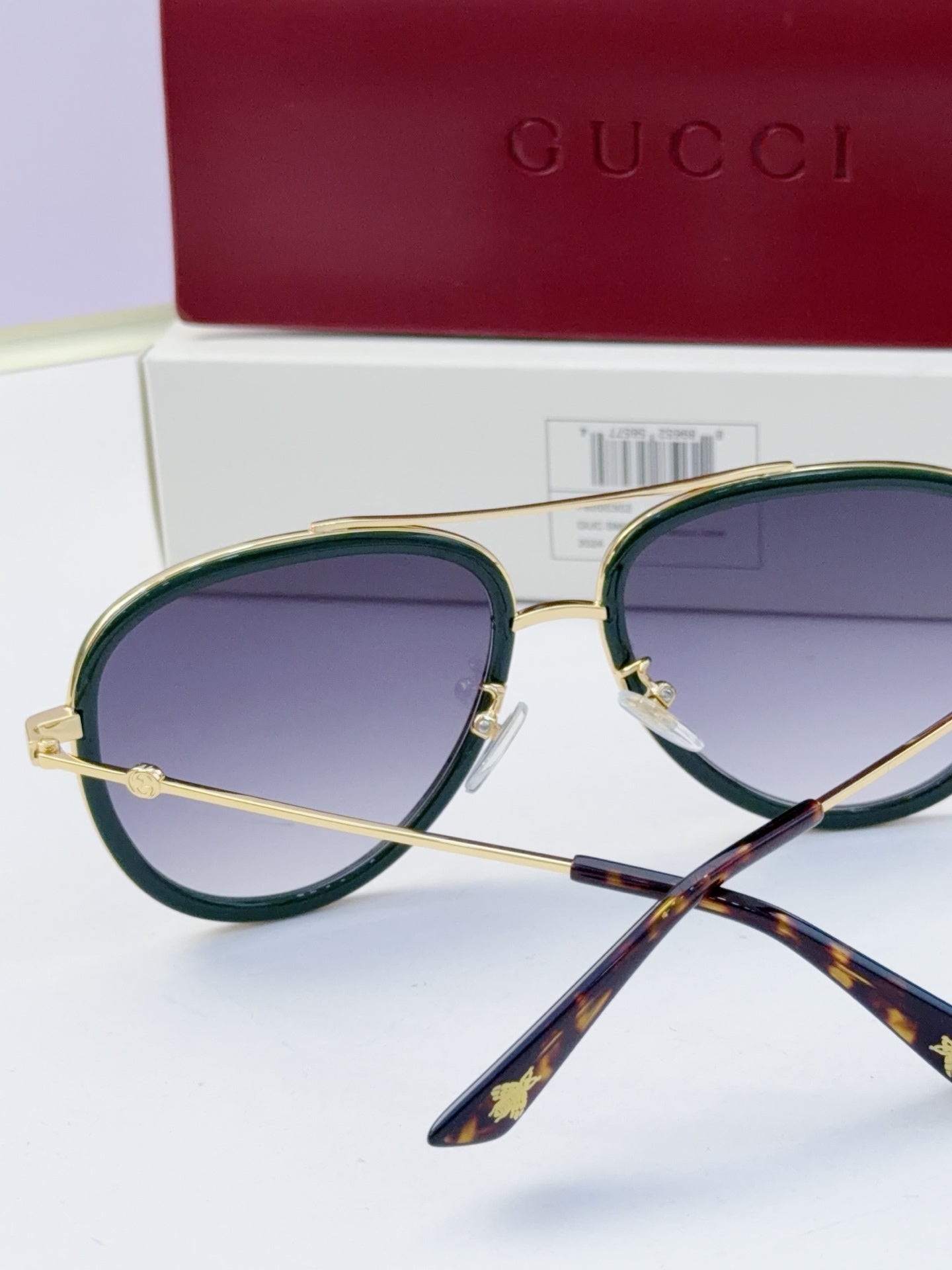 Gucci glasses with purple lenses and gold metal frames, dark green accent and tortoise temples