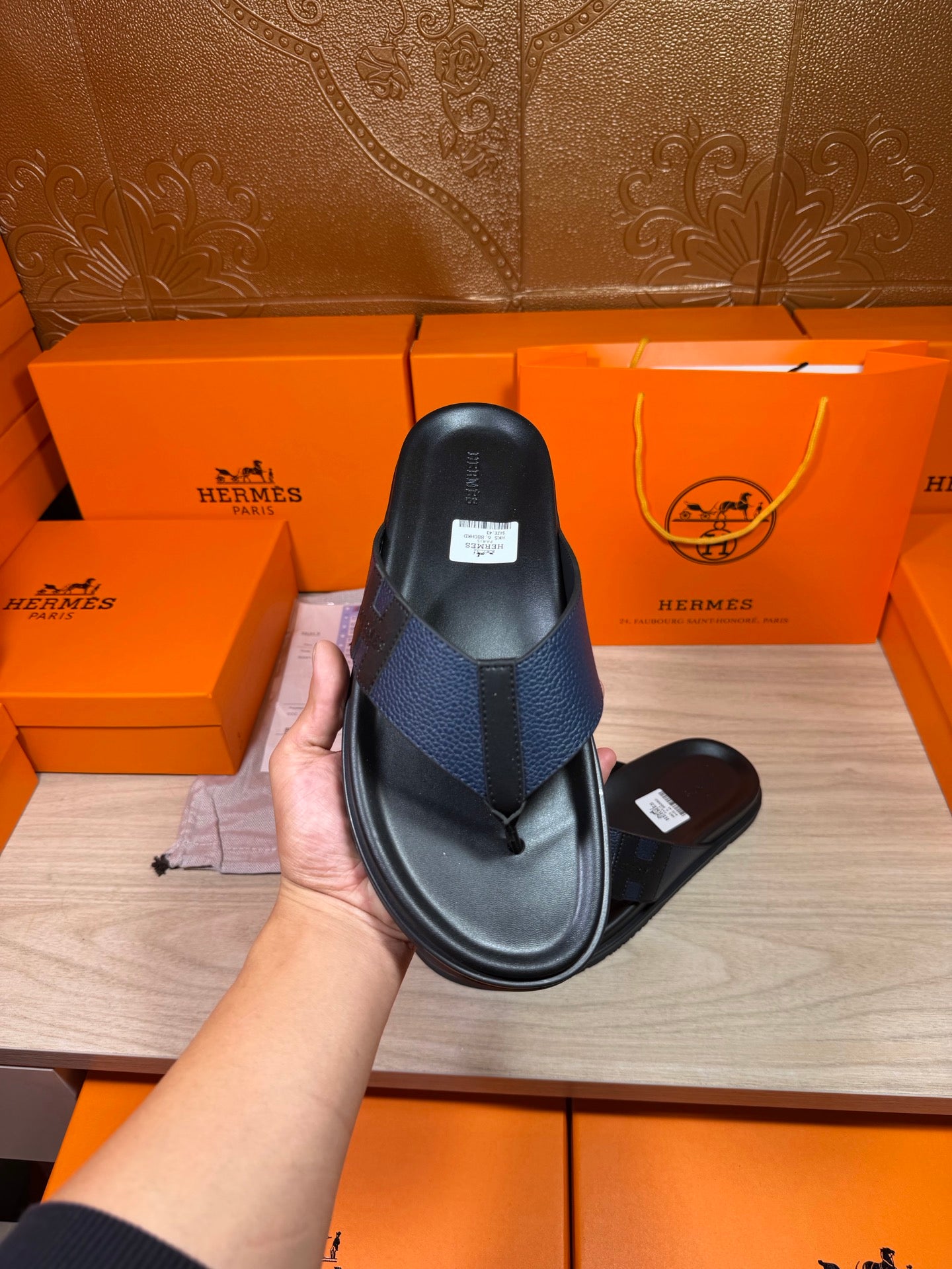 Black slide sandal close-up held in hand, textured strap and flat sole