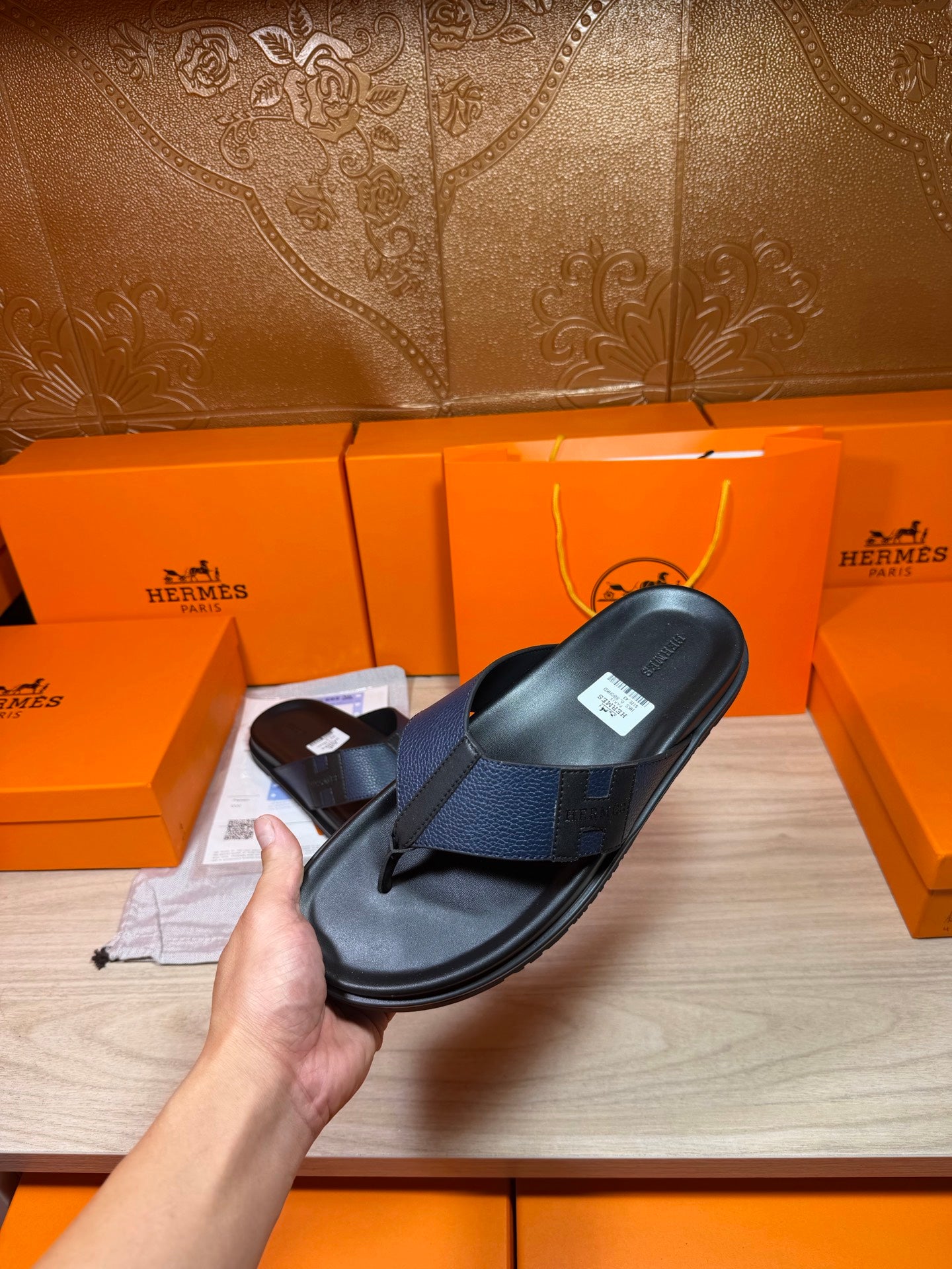 Black slide sandal held in hand, textured crossover strap, side angle
