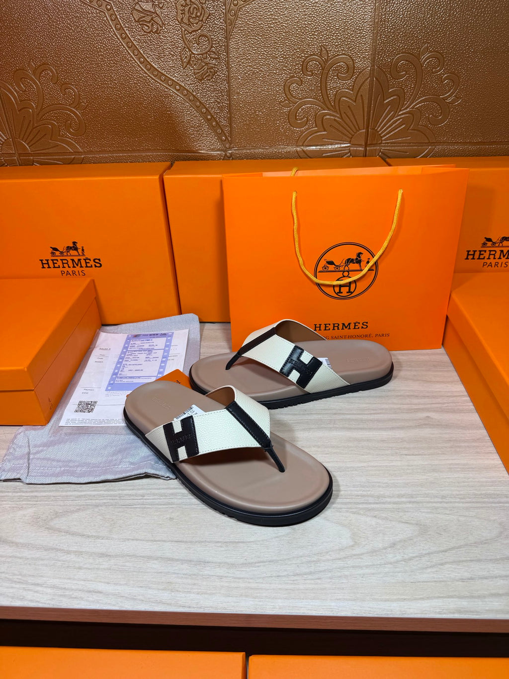 Luxury Hermes sandals with cream soles, white strap, and black H buckle detail