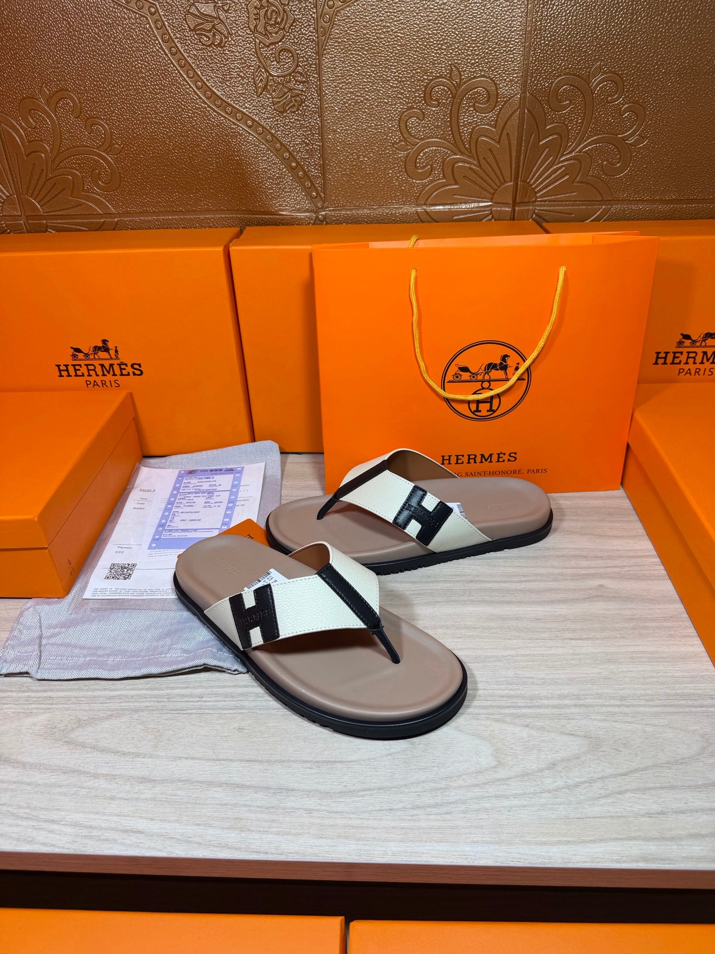 Luxury Hermes sandals with cream soles, white strap, and black H buckle detail