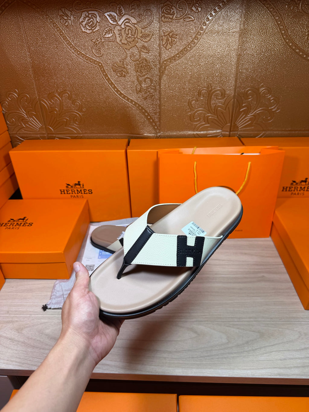 Luxury Hermes slide sandal with cream footbed, white strap, black H buckle detail