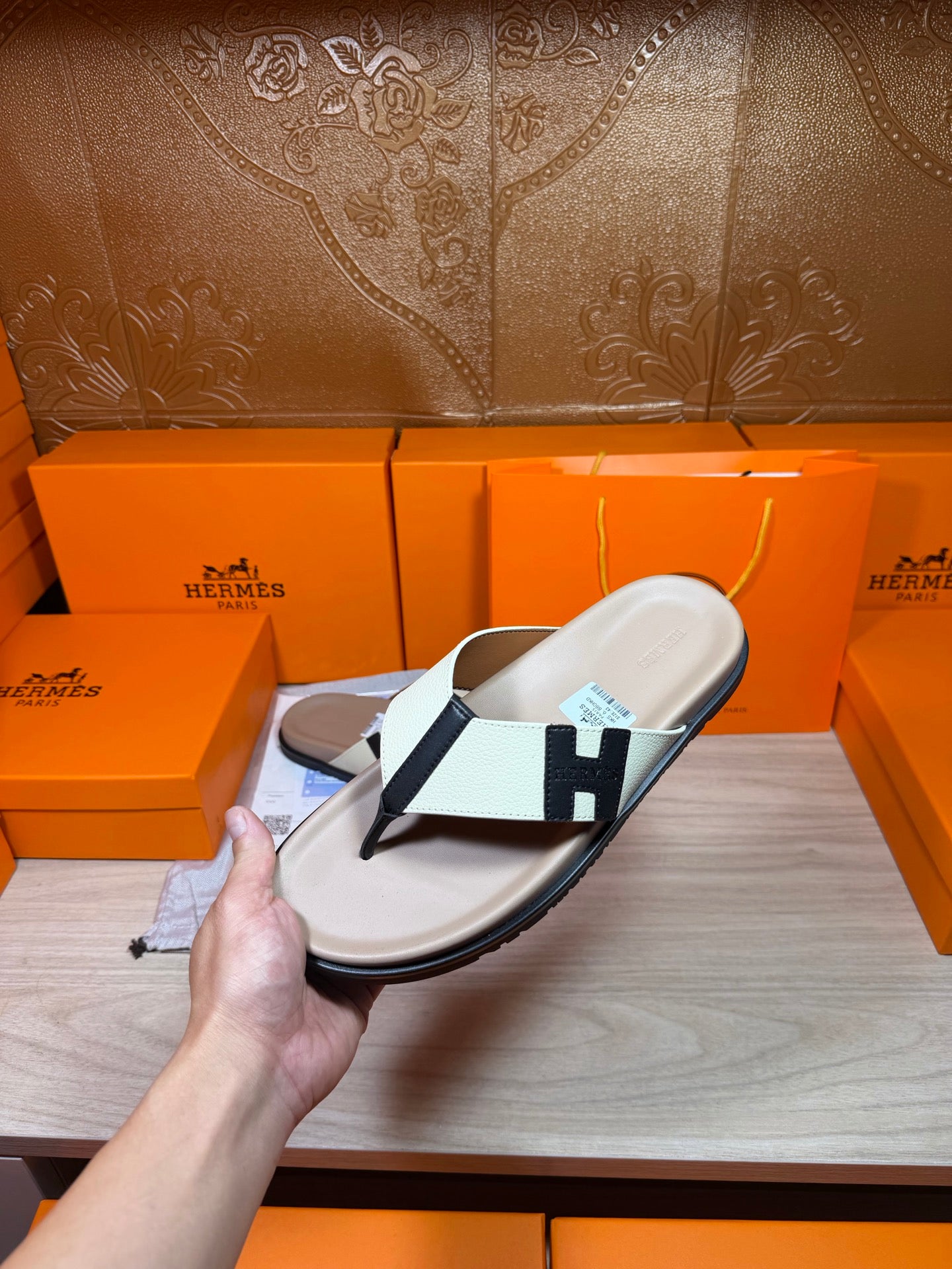 Luxury Hermes slide sandal with cream footbed, white strap, black H buckle detail