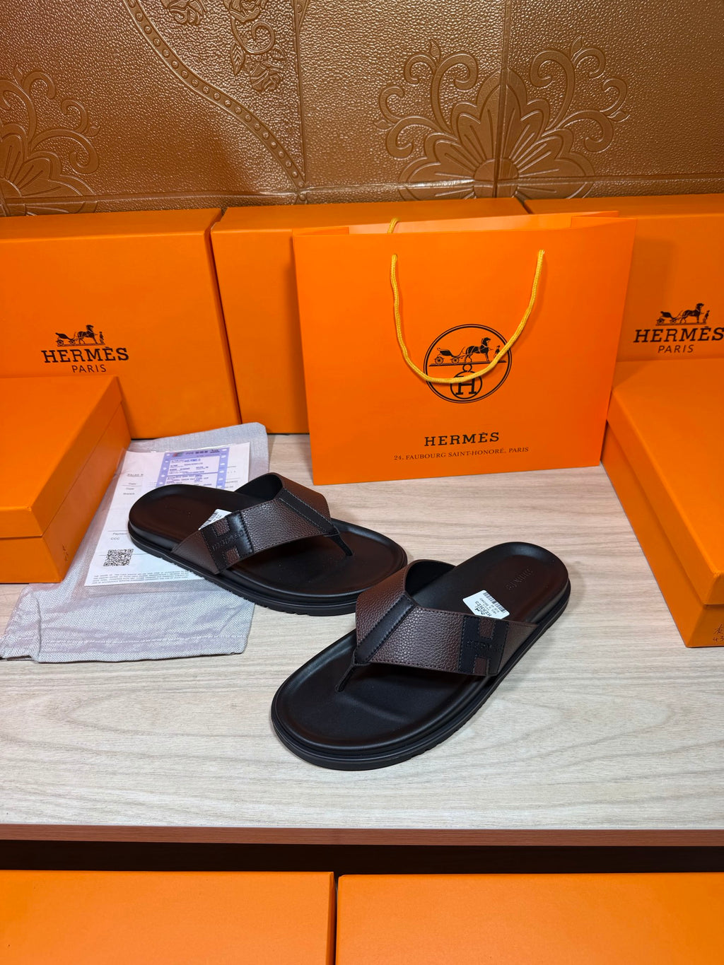 Black leather thong sandals with textured crossover straps, laid side by side