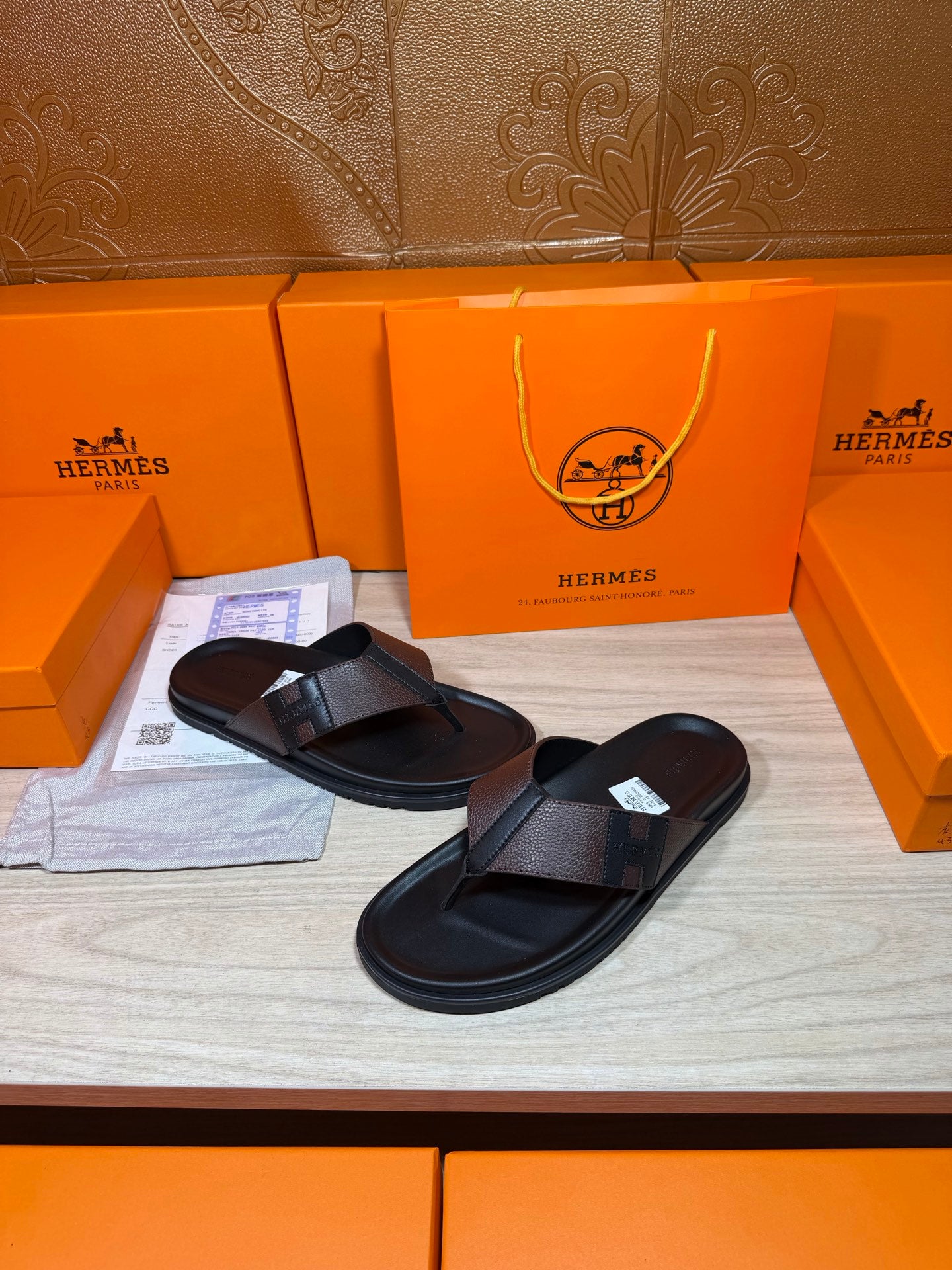 Black leather thong sandals with textured crossover straps, laid side by side