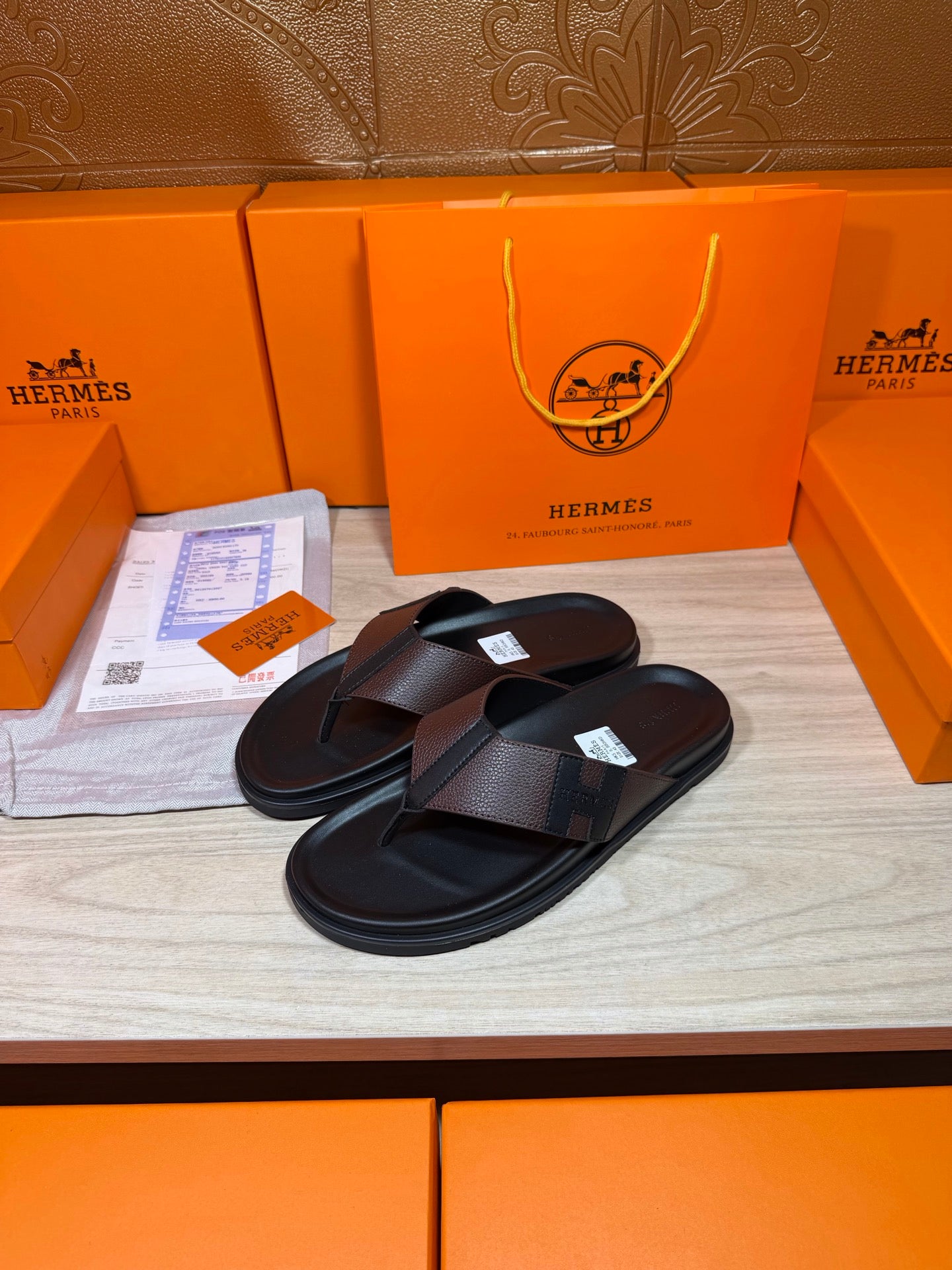Black leather thong sandals with textured crossover strap, shown on display
