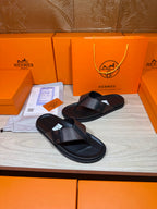 Pair of black leather thong sandals with textured crossover straps on display