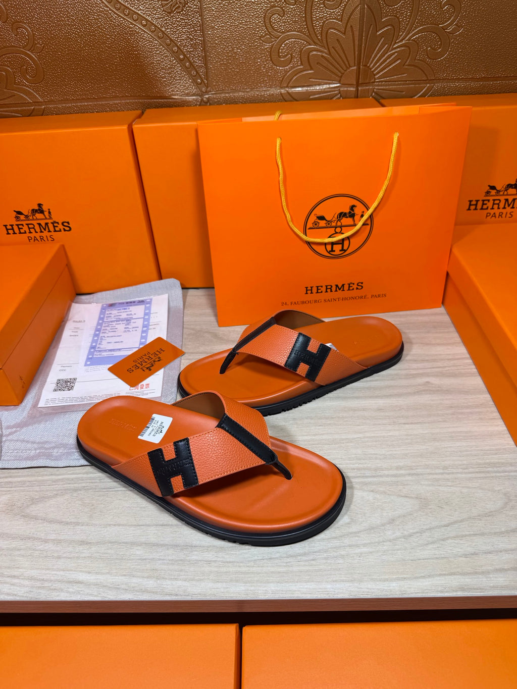 Hermes orange flip-flop sandals with black H strap and thick rubber sole edge