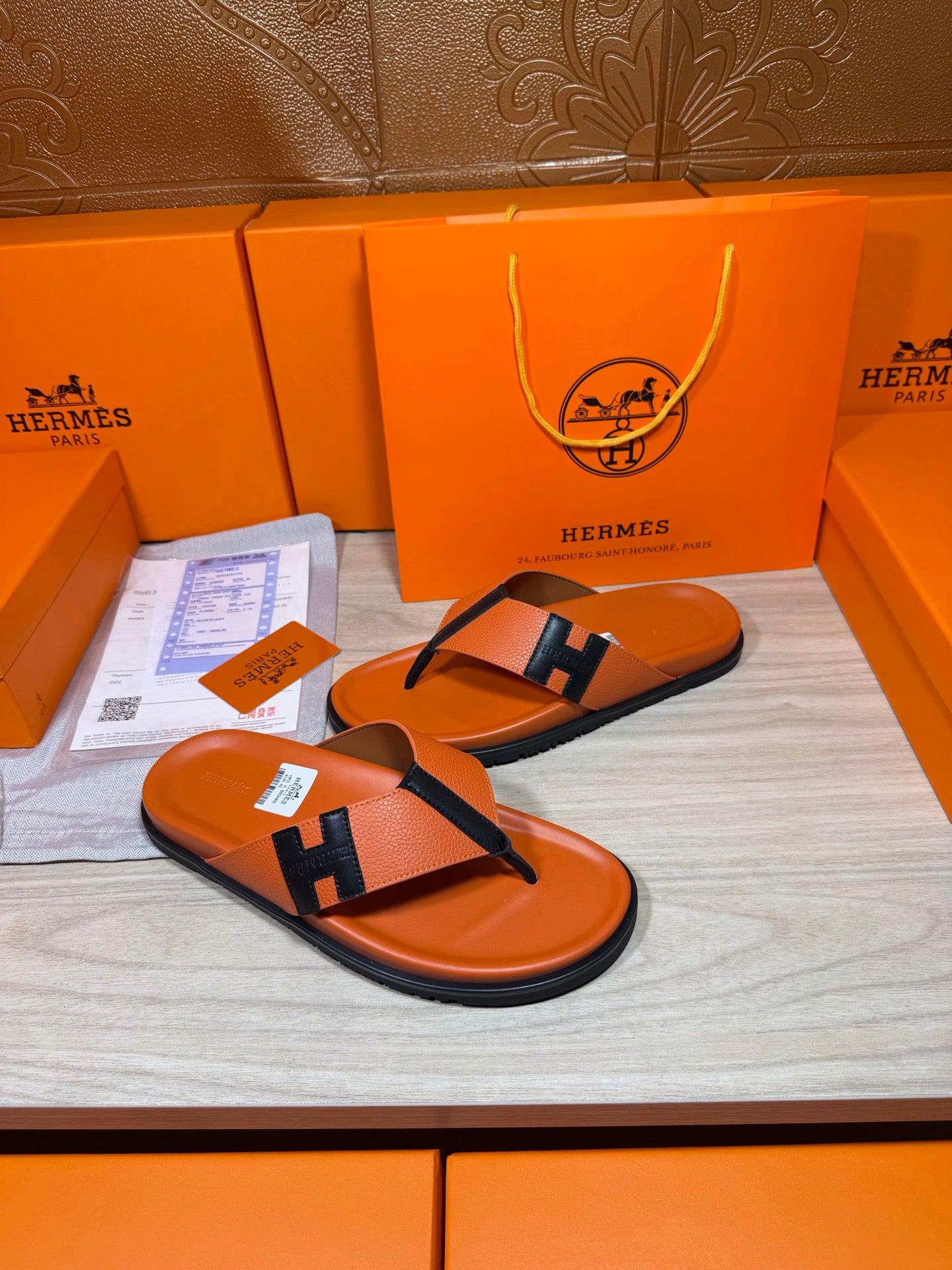 Hermes orange flip-flop sandals with black H strap and thick rubber sole edge
