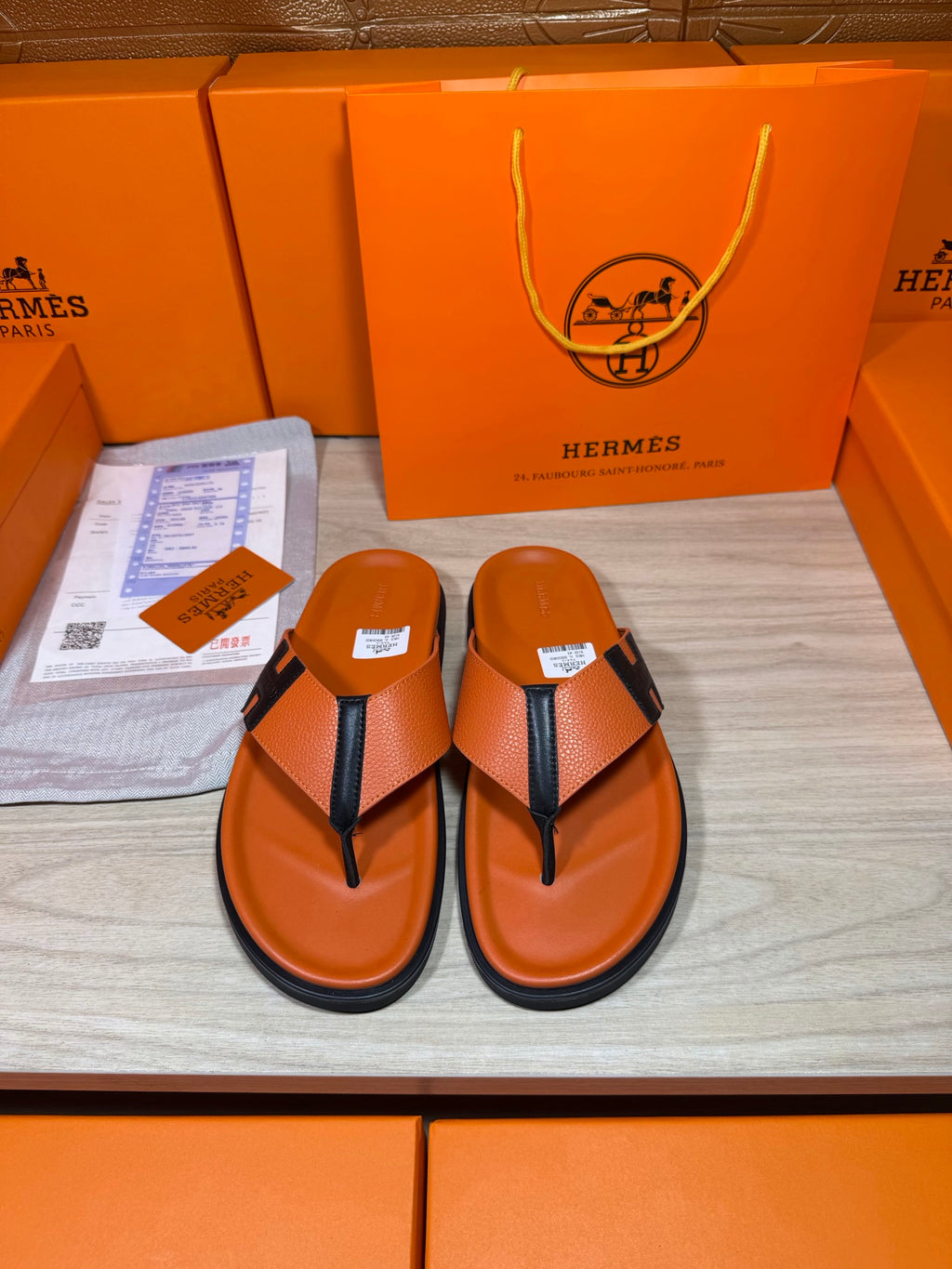 Orange Hermes leather flip-flop sandals with black thong strap and H logo