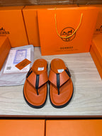 Orange Hermes leather flip-flop sandals with black thong strap and H logo