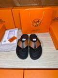 Pair of black thong sandals with tan strap and H buckle detail