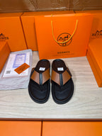 Pair of black thong sandals with tan strap and H buckle detail