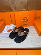 Black thong sandals with tan strap and H buckle detail, side view
