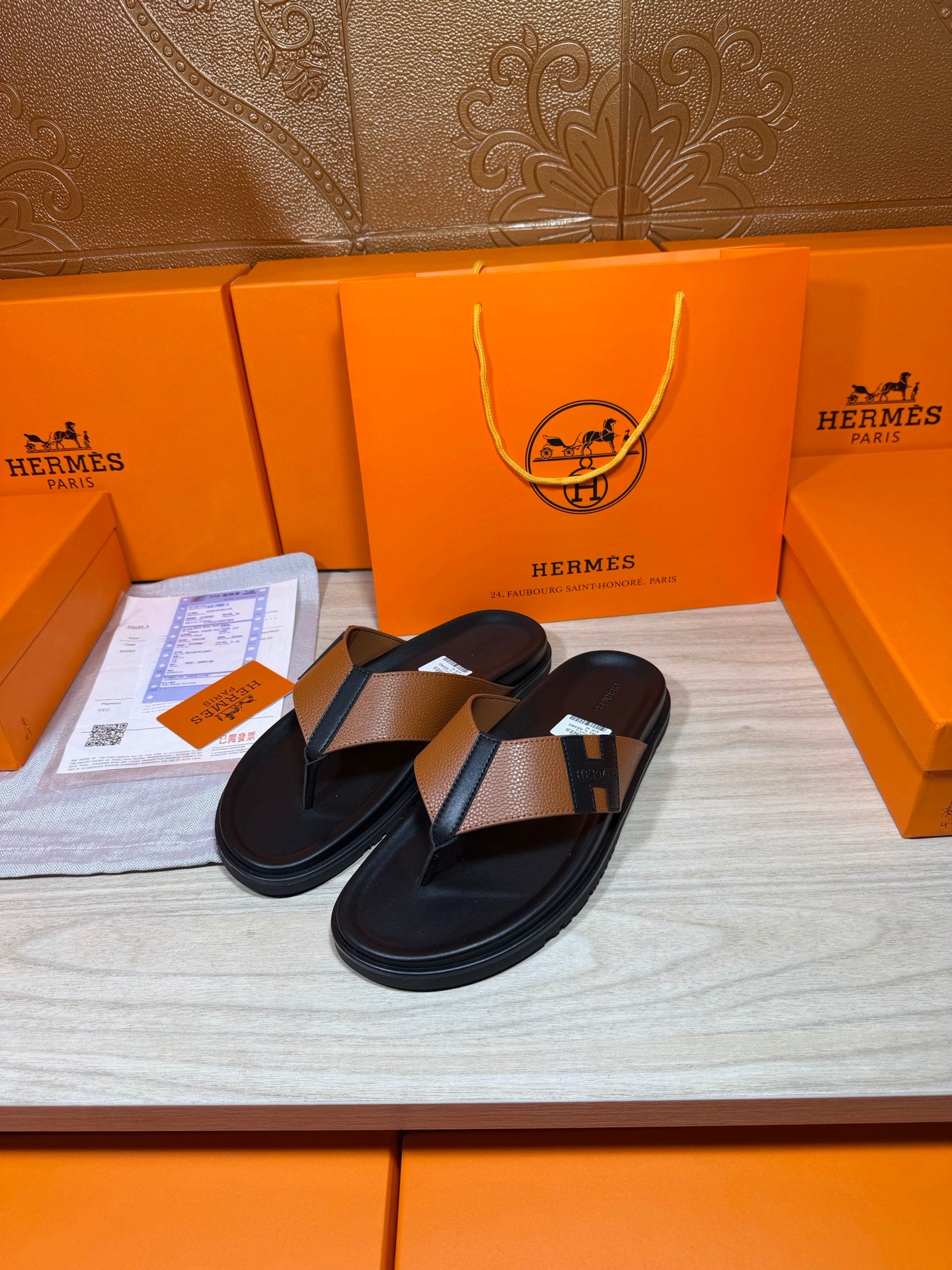 Black thong sandals with tan strap and H buckle detail, side view