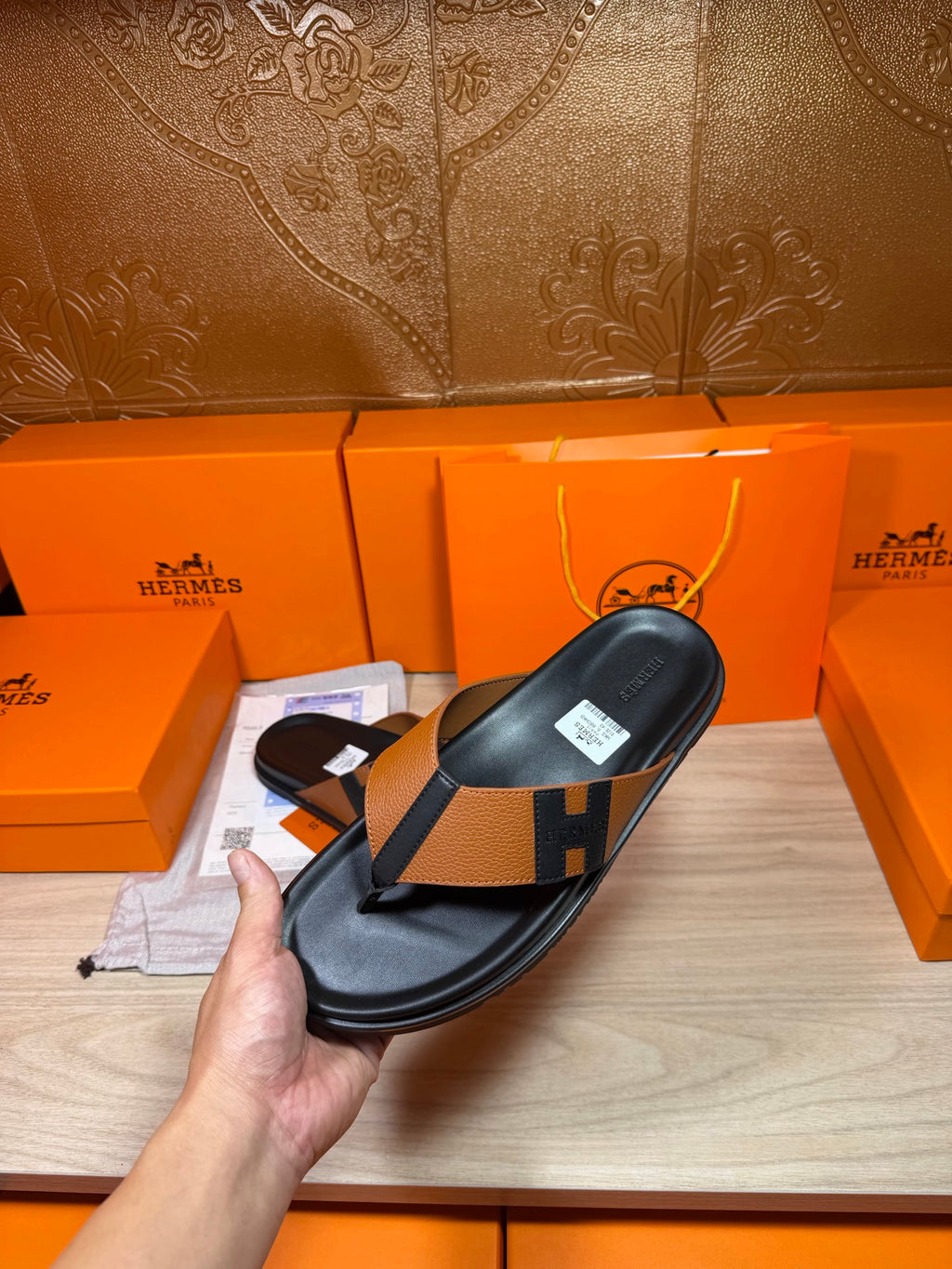 Single black thong sandal with tan strap and H buckle detail, held