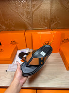 Single black thong sandal with tan strap and H buckle detail, held