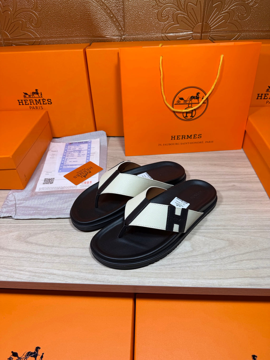 Pair of black thong sandals with white strap panels and square logo buckle