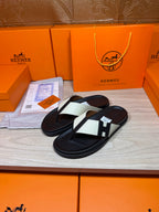 Pair of black thong sandals with white strap panels and square logo buckle