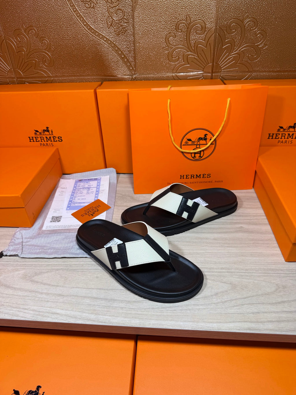 Black thong sandals with white strap panels and square logo buckle detail on display
