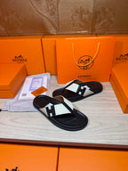 Black thong sandals with white strap panels and square logo buckle detail on display