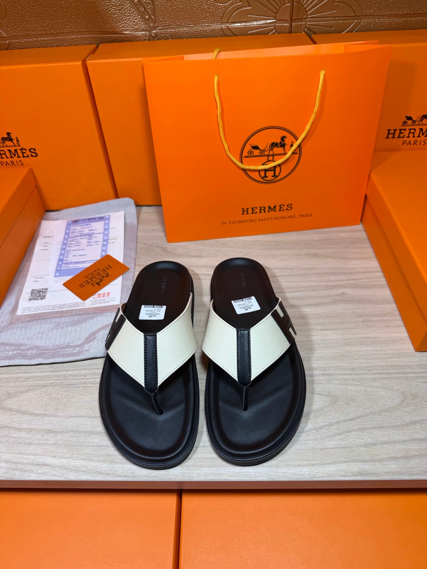 Black thong sandals with white strap panels and a square logo buckle detail